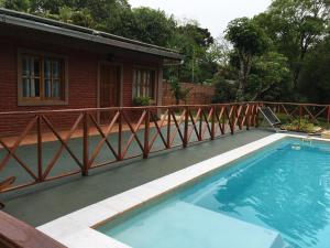 a swimming pool with a wooden railing on a deck at Posada Enki in Puerto Iguazú