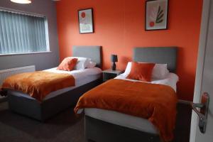 2 camas en una habitación con paredes de color naranja en Stylish 3 Bedroom House Near NEC, City Centre, en Birmingham