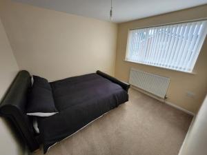 a black couch in a room with a window at 3 bed House Lovely & Modern in Whitefield