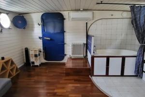 里昂的住宿－Appartement dans Péniche atypique et idyllique à Confluence，浴室设有蓝色门和浴缸。