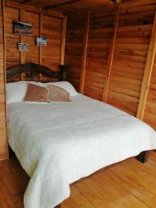 a bed in a room with wooden walls at Cabañas Guatavita in Guatavita