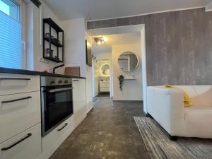 a kitchen with a stove and a couch in a room at Gleis 12 , kontaktloser 24-7-Check In, barrierefrei ,Smart TV, W-LAN, Parkplatz kostenlos in Bückeburg