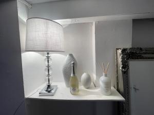 a lamp on a shelf with vases and a mirror at Cwtch Cardiff Bay in Cardiff