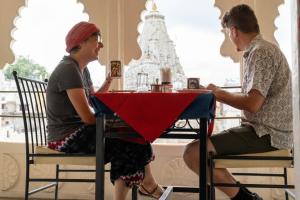 two people sitting at a table in front of a window at Baba Palace - A Heritage Hotel, Udaipur in Udaipur