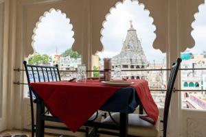 a red table with chairs and a view of a building at Baba Palace - A Heritage Hotel, Udaipur in Udaipur