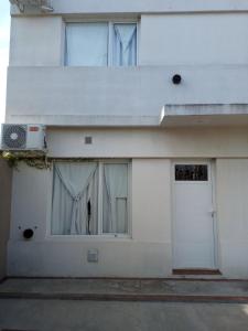 uma casa branca com uma porta e uma janela em Jugueze Tres Arroyos II em Tres Arroyos