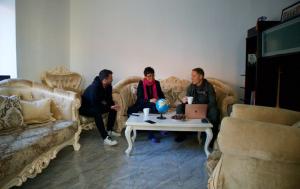 GOT Prishtina Hostel في بريشتيني: مجموعة من الناس يجلسون في غرفة معيشة مع طاولة