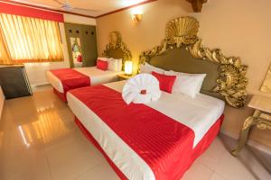 2 camas en una habitación de hotel con sábanas rojas y blancas en Hotel Las Golondrinas, en Playa del Carmen