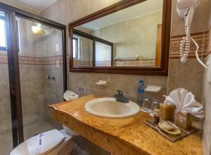 y baño con lavabo, aseo y espejo. en Hotel Las Golondrinas en Playa del Carmen