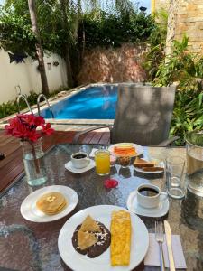 a table topped with plates of food next to a pool at Hotel Las Golondrinas in Playa del Carmen