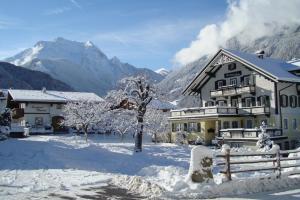 una casa en la nieve con montañas en el fondo en Ferienwohnungen Kröll - Appartements Viktoria und Landhaus Maria, en Mayrhofen