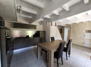 eine Küche und ein Esszimmer mit einem Holztisch und Stühlen in der Unterkunft La Petite Maison Neuvecelle - Maison de village in Neuvecelle