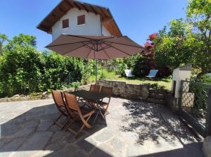 einen Tisch und Stühle mit Sonnenschirm auf einer Terrasse in der Unterkunft La Petite Maison Neuvecelle - Maison de village in Neuvecelle