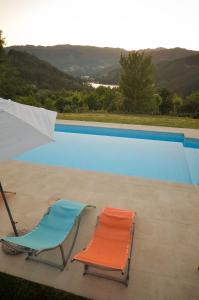 twee stoelen en een parasol naast een zwembad bij Cantinho da Pedra in Vieira do Minho