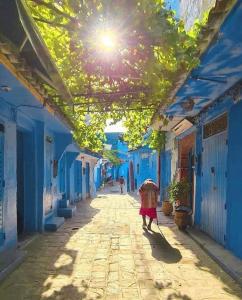 eine Person, die mit einem Regenschirm durch eine Gasse geht in der Unterkunft Dar El Fanne in Chefchaouen