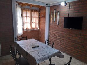 a dining room with a table and a tv on a brick wall at Alojamiento Puesta del Sol in El Bolsón