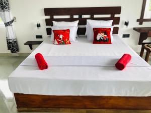 Una gran cama blanca con almohadas rojas. en Indika's Apartment en Hikkaduwa