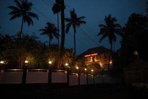 a building at night with palm trees and lights at Athirappilly Ambady Resort in Athirappilly
