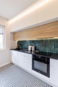 a kitchen with white cabinets and a tile floor at Bielany Apart Joanny obok metra in Warsaw