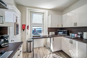 a kitchen with white cabinets and a window at Broughty Ferry Riverview Apt -3 bedroom -Sleeps 7 in Broughty Ferry