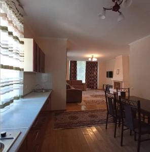 uma cozinha e sala de estar com mesa e cadeiras em Raduga West Pineforest - коттедж в аренду на Иссык-Куле em Koshkolʼ