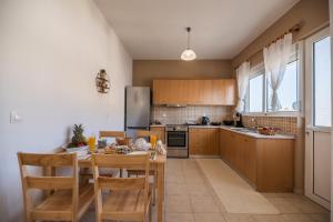 a kitchen with wooden cabinets and a table with chairs at Katerina's House in Afantou