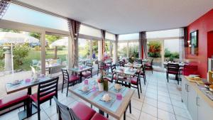uma sala de jantar com mesas, cadeiras e janelas em Hôtel de France Contact-Hôtel em Évian-les-Bains
