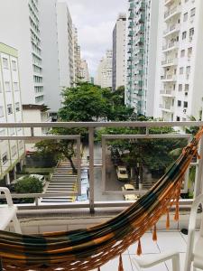 a hammock on a balcony in a city at Relax Pitangueiras Guarujá in Guarujá