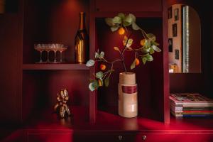 een rode plank met een fles en een vaas met een plant bij Coco’s Buitenhuisje in Nunspeet