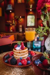 a table topped with pancakes and berries with a glass of orange juice at Coco’s Buitenhuisje in Nunspeet