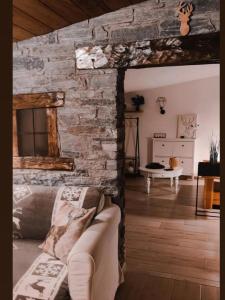 - un salon avec un canapé et un mur en pierre dans l'établissement Il nido di Lele e Schina, à Arvier