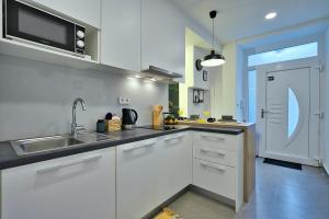 une cuisine blanche avec un évier et un micro-ondes dans l'établissement Aurea City Center Apartment Zagreb, à Zagreb