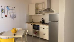 a small kitchen with a table and a refrigerator at Carolina Apartments - Monolocale in Capo dʼOrlando