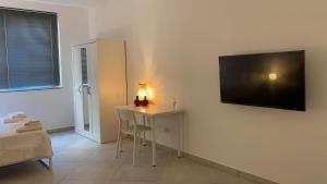 a room with a table and a television on a wall at Carolina Apartments - Monolocale in Capo dʼOrlando