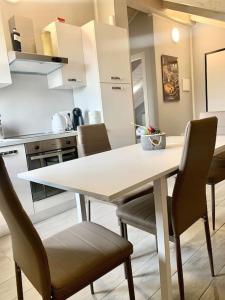 - une cuisine avec une table et des chaises blanches dans l'établissement Appartamento Turin Airport, à Leinì