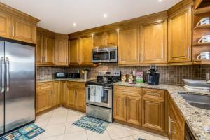 a kitchen with wooden cabinets and stainless steel appliances at OCEAN VACATION BREEZE in Lantana