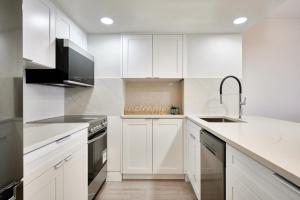 a white kitchen with white cabinets and a sink at Drake950 in Vancouver