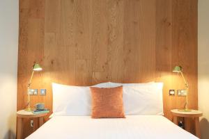 a bed with a wooden headboard and two lamps at Cairn Hotel & Apartments in Edinburgh