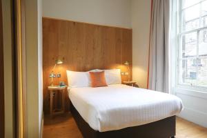 um quarto com uma cama grande e uma janela em Cairn Hotel & Apartments em Edimburgo