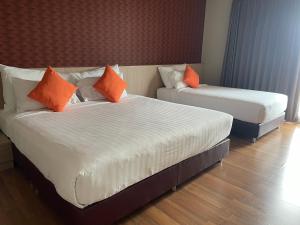 two beds with orange pillows in a hotel room at Tonaoi Grand Hotel in Hat Yai