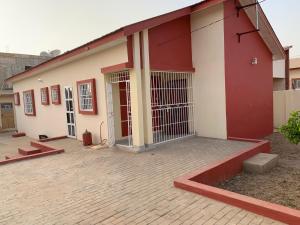 a red and white building with a gate at Cheerful 3 bedroom bungalow, Fatty Boulevard in Madina Sey Kunda