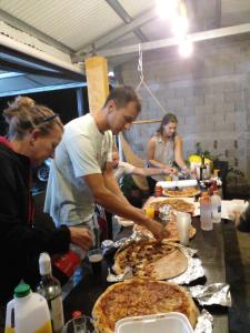 a group of people standing around a table with pizzas at Cabañas Martina Surf Playa Guanico in Pedregal