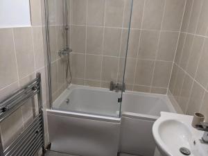 y baño con ducha, bañera blanca y lavamanos. en 4 Bedroom Home Near York Racecourse, en York