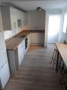 una cucina con armadietti bianchi e pavimenti in legno di 4 Bedroom Home Near York Racecourse a York