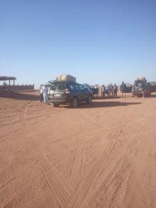 un gruppo di persone e veicoli in un deserto di Auberge étoiles iriki a Foum Zguid