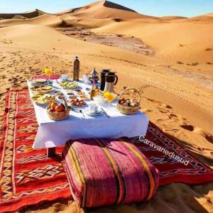 una mesa con comida en el desierto en Auberge étoiles iriki en Foum Zguid