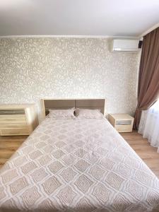 ein Schlafzimmer mit einem Bett mit einer weißen Bettdecke in der Unterkunft Уютные апартаменты в центре города in Oral
