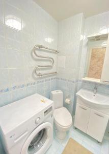 ein Badezimmer mit einer Waschmaschine und einem WC in der Unterkunft Уютные апартаменты в центре города in Oral