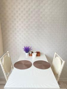 einen Tisch mit 2 Stühlen und einen weißen Tisch mit Blumen in der Unterkunft Уютные апартаменты в центре города in Oral