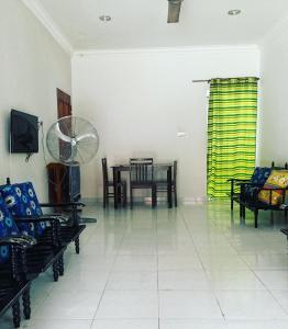 uma sala de estar com uma mesa e cadeiras e uma ventoinha em Hj Hassan Guest House Bungalow B em Kuala Terengganu